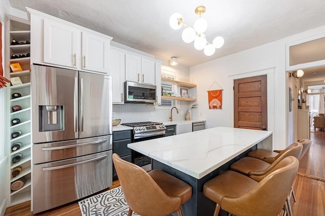 kitchen with open shelves, wood finished floors, white cabinets, backsplash, and stainless steel appliances