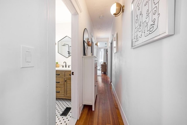 hallway with baseboards, a sink, and hardwood / wood-style floors