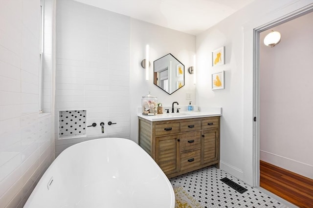 full bathroom featuring visible vents, a freestanding tub, baseboards, vanity, and tile patterned floors