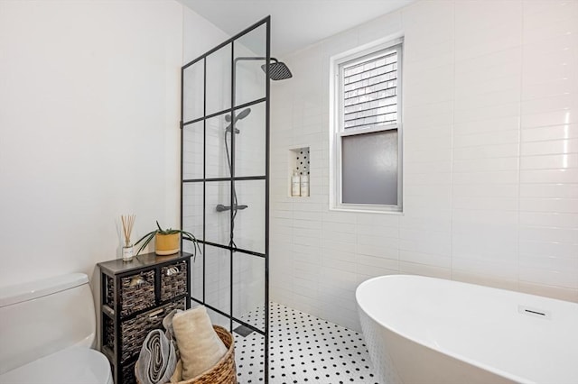 bathroom with a walk in shower, a soaking tub, toilet, and tile walls