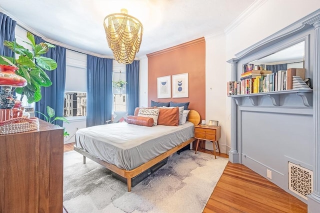 bedroom featuring crown molding, visible vents, wood finished floors, and a notable chandelier
