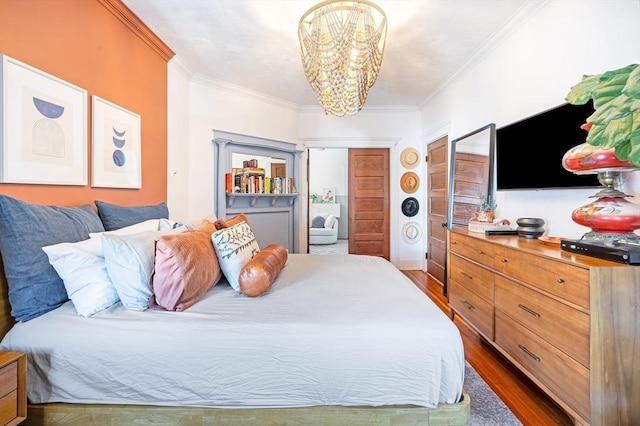 bedroom with crown molding, an inviting chandelier, dark wood finished floors, and a closet