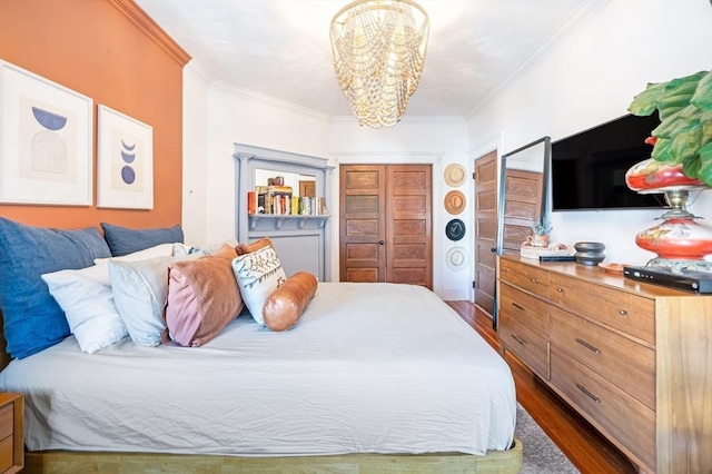 bedroom with a closet, an inviting chandelier, ornamental molding, and dark wood-type flooring