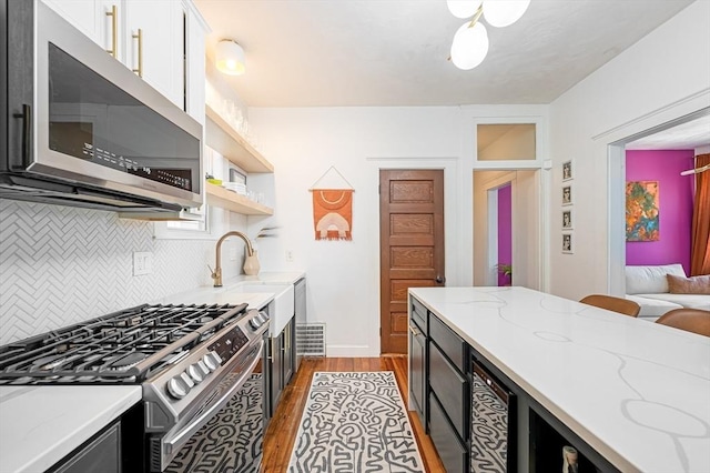 kitchen featuring light stone countertops, dark wood-type flooring, white cabinets, tasteful backsplash, and appliances with stainless steel finishes