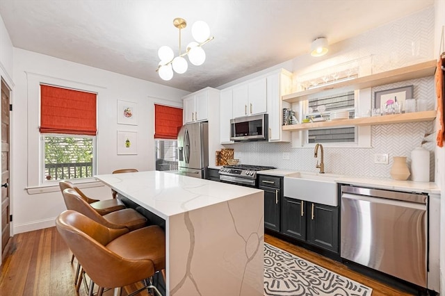 kitchen with a kitchen island, stainless steel appliances, a kitchen breakfast bar, and hardwood / wood-style floors