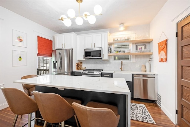 kitchen featuring decorative backsplash, a breakfast bar, baseboards, a sink, and appliances with stainless steel finishes