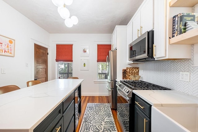 kitchen featuring a kitchen island, dark wood-type flooring, white cabinets, appliances with stainless steel finishes, and backsplash