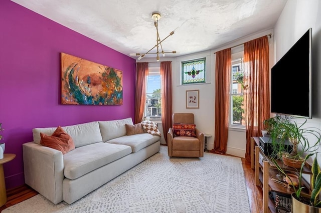 living room featuring baseboards, an inviting chandelier, and wood finished floors