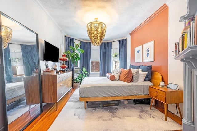 bedroom featuring ornamental molding, multiple windows, light wood-style flooring, and a notable chandelier