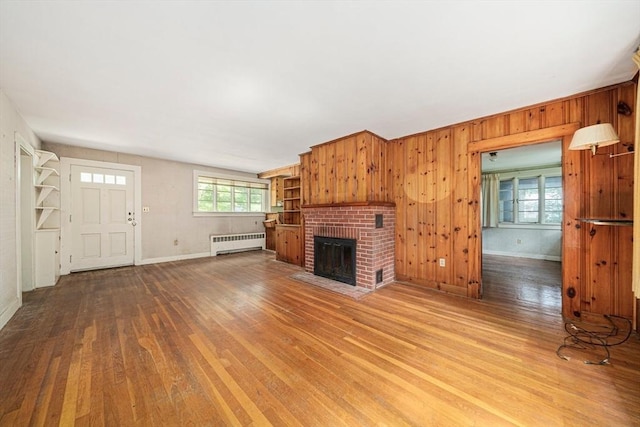 36 Grove St, Hanover, MA 02339 - unfurnished living room with radiator heating unit, wood finished floors, a brick fireplace, and wood walls