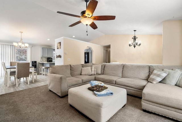 living room featuring lofted ceiling, ceiling fan with notable chandelier, and light hardwood / wood-style floors