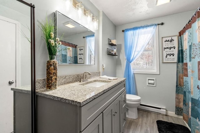 bathroom with vanity, toilet, hardwood / wood-style floors, and a baseboard heating unit