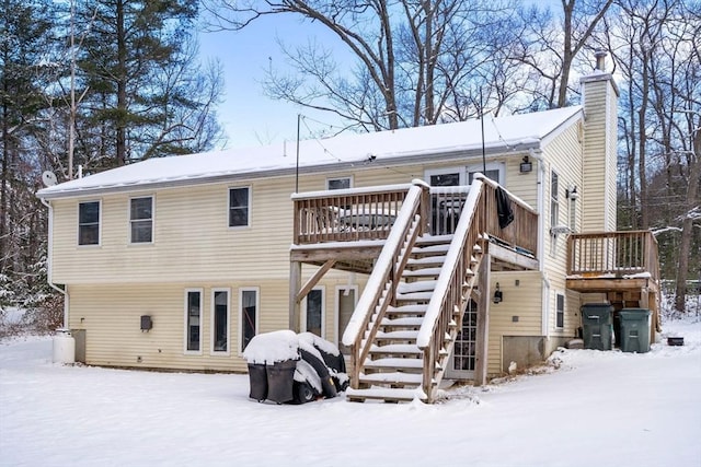 snow covered rear of property with a wooden deck