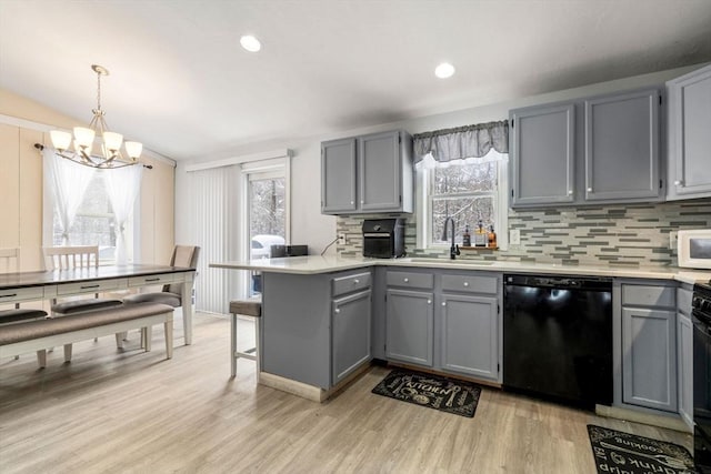 kitchen featuring pendant lighting, gray cabinets, kitchen peninsula, and dishwasher