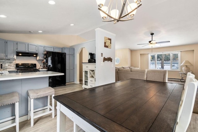 dining room featuring lofted ceiling, a baseboard heating unit, light hardwood / wood-style floors, and ceiling fan