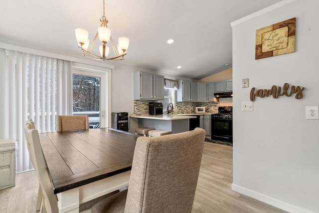 dining space featuring lofted ceiling, sink, light hardwood / wood-style flooring, and a chandelier