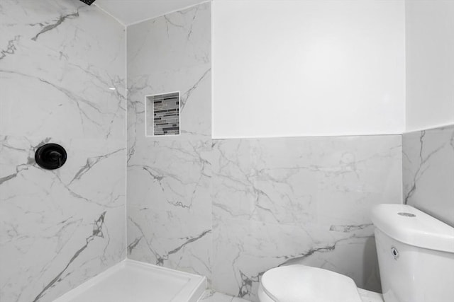 bathroom with tile walls, toilet, and tiled shower