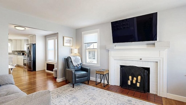 living room with a fireplace, wood finished floors, and baseboards