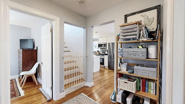 hall featuring light wood-style floors and baseboards