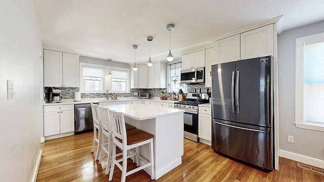 kitchen featuring appliances with stainless steel finishes, decorative backsplash, light wood-style flooring, and white cabinets