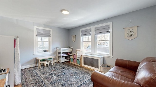 recreation room with radiator heating unit, baseboards, and wood finished floors