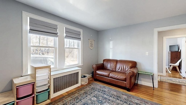 living area with radiator, baseboards, and wood finished floors