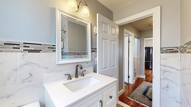 bathroom with wood finished floors, vanity, and tile walls