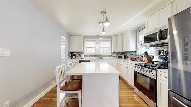 kitchen featuring stainless steel appliances, a breakfast bar, a sink, decorative backsplash, and light wood finished floors