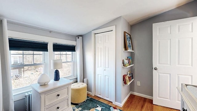 interior space with light wood-style floors, lofted ceiling, and baseboards