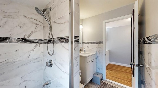 full bathroom with a shower, tile walls, toilet, vanity, and wood finished floors