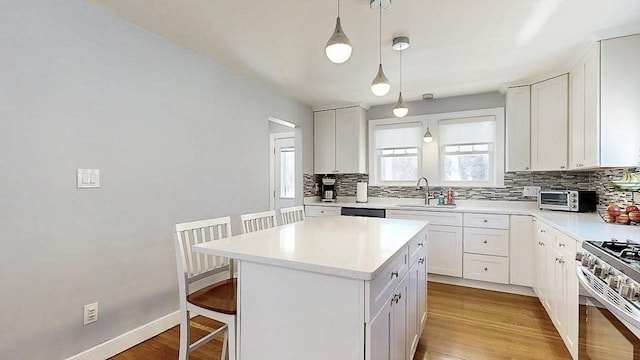 kitchen with light countertops, decorative backsplash, a sink, and a kitchen breakfast bar