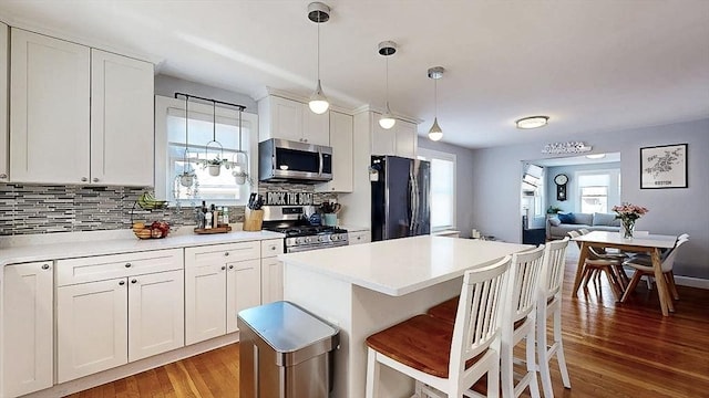 kitchen featuring light wood finished floors, tasteful backsplash, appliances with stainless steel finishes, and light countertops