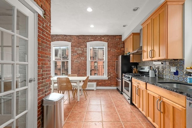 293-295 Commonwealth Ave Unit 3C, Boston, MA 02111 - kitchen featuring stainless steel range with gas stovetop, brick wall, wall chimney exhaust hood, dark countertops, and decorative backsplash