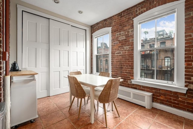 293-295 Commonwealth Ave Unit 3C, Boston, MA 02111 - dining room featuring brick wall, radiator heating unit, healthy amount of natural light, and light tile patterned flooring