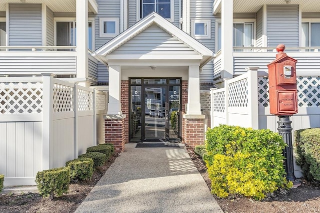 view of exterior entry with brick siding and fence