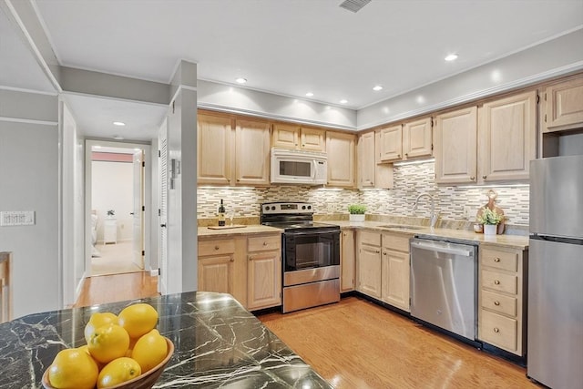 kitchen with light brown cabinets, appliances with stainless steel finishes, and a sink