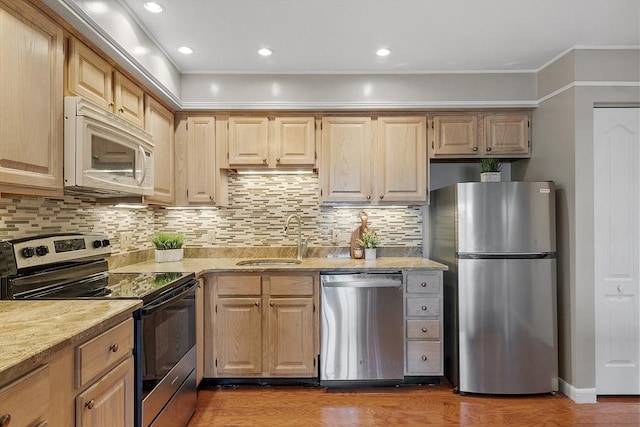 kitchen featuring tasteful backsplash, wood finished floors, appliances with stainless steel finishes, a sink, and crown molding