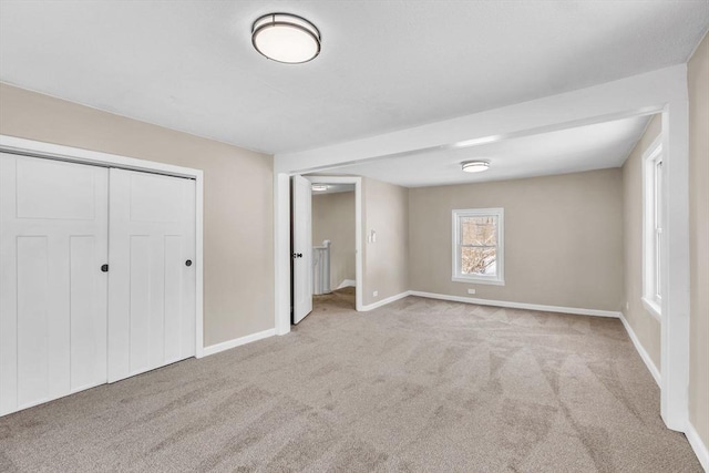 unfurnished bedroom with light colored carpet and a closet