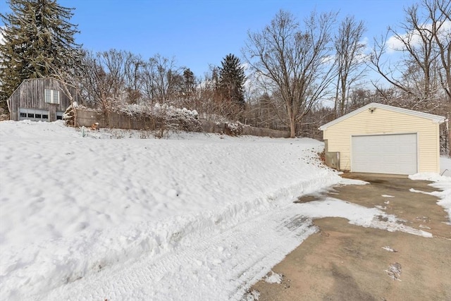 yard covered in snow featuring an outbuilding and a garage