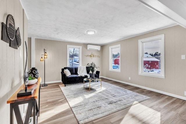 living area with an AC wall unit and light hardwood / wood-style floors