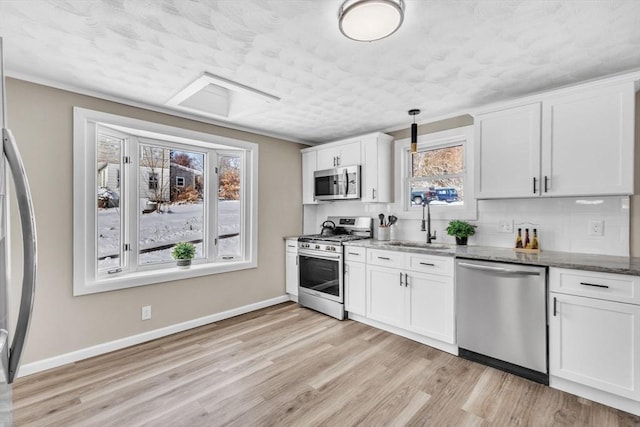 kitchen featuring light stone counters, hanging light fixtures, stainless steel appliances, and white cabinets