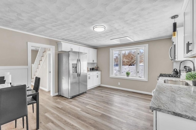 kitchen featuring sink, white cabinetry, light stone counters, decorative light fixtures, and appliances with stainless steel finishes