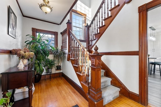 foyer entrance featuring hardwood / wood-style floors, crown molding, stairway, and baseboards