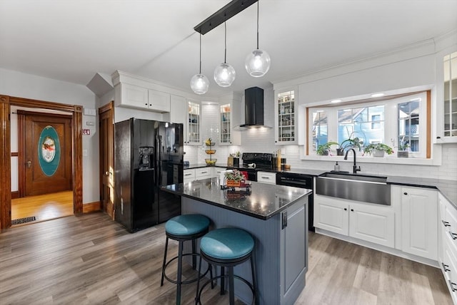 kitchen featuring light wood-style flooring, a sink, electric stove, wall chimney range hood, and black fridge