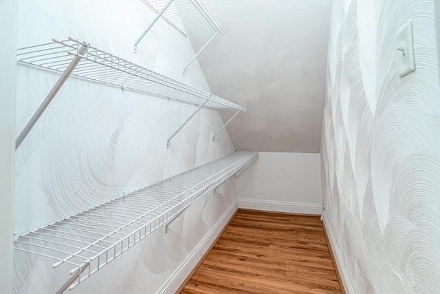 walk in closet with wood finished floors and lofted ceiling