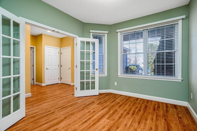 empty room featuring french doors, baseboards, and wood finished floors