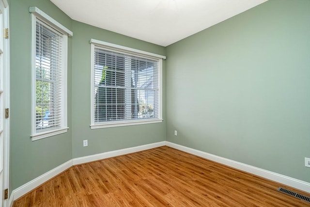 empty room featuring visible vents, baseboards, and wood finished floors