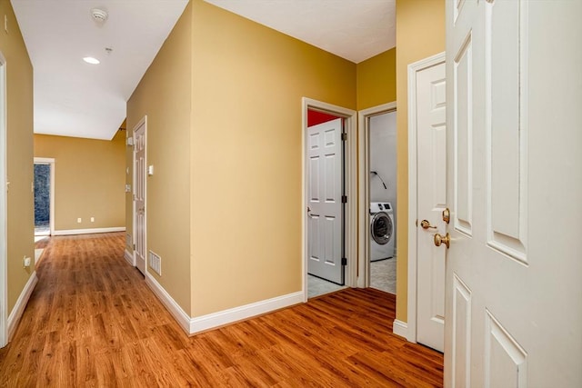 corridor featuring visible vents, baseboards, washer / dryer, and light wood finished floors