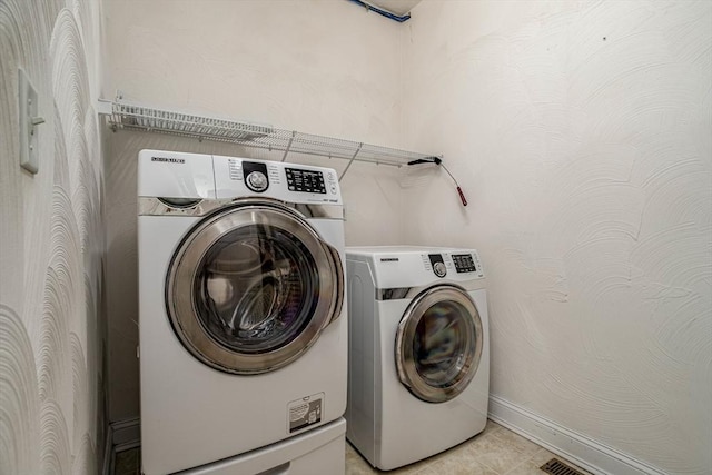 clothes washing area featuring visible vents, light tile patterned floors, separate washer and dryer, and laundry area