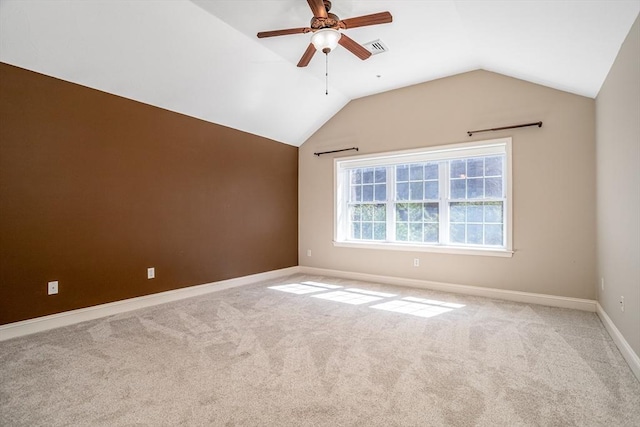 carpeted spare room with visible vents, baseboards, vaulted ceiling, and ceiling fan